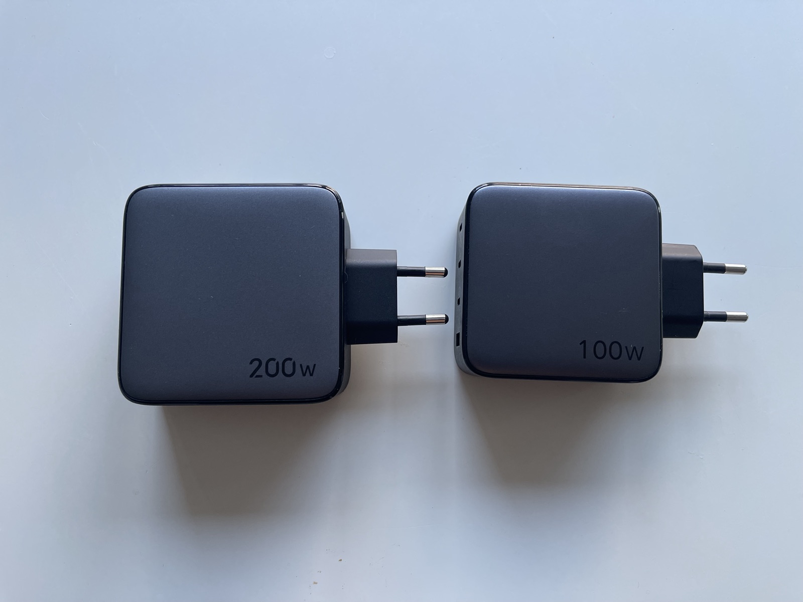 A 200 W and a 100 W UGREEN GaN charger side by side, nearly identical in size